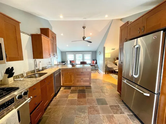 a kitchen with stainless steel appliances a stove a sink dishwasher a refrigerator white cabinets and wooden floor