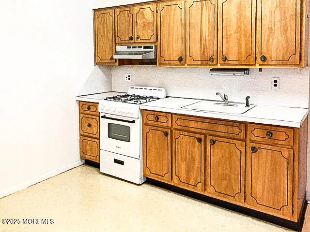 a kitchen with stainless steel appliances granite countertop a sink a stove and white cabinets