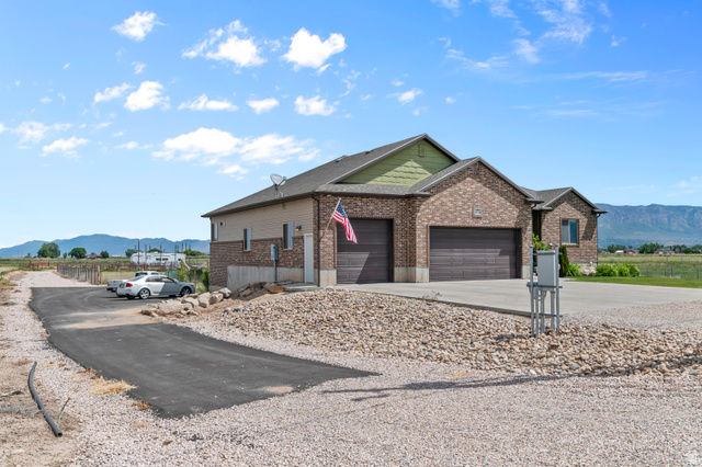 5702 950 North Ogden, UT 84404 - Photo 4 of 36 Brick exterior with a multi-car garage, concrete driveway, and a paved approach