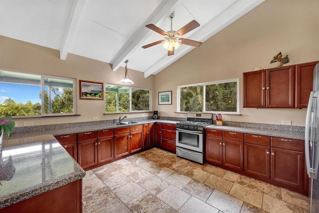 143 Alalele Place Hana, HI 96713 - Photo 11 of 50 a large kitchen with stainless steel appliances granite countertop wooden cabinets a sink a stove a dining table and chairs