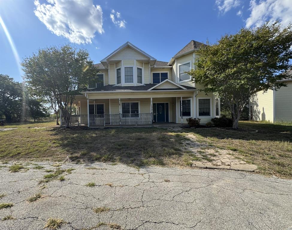 Victorian home with a porch and a front lawn