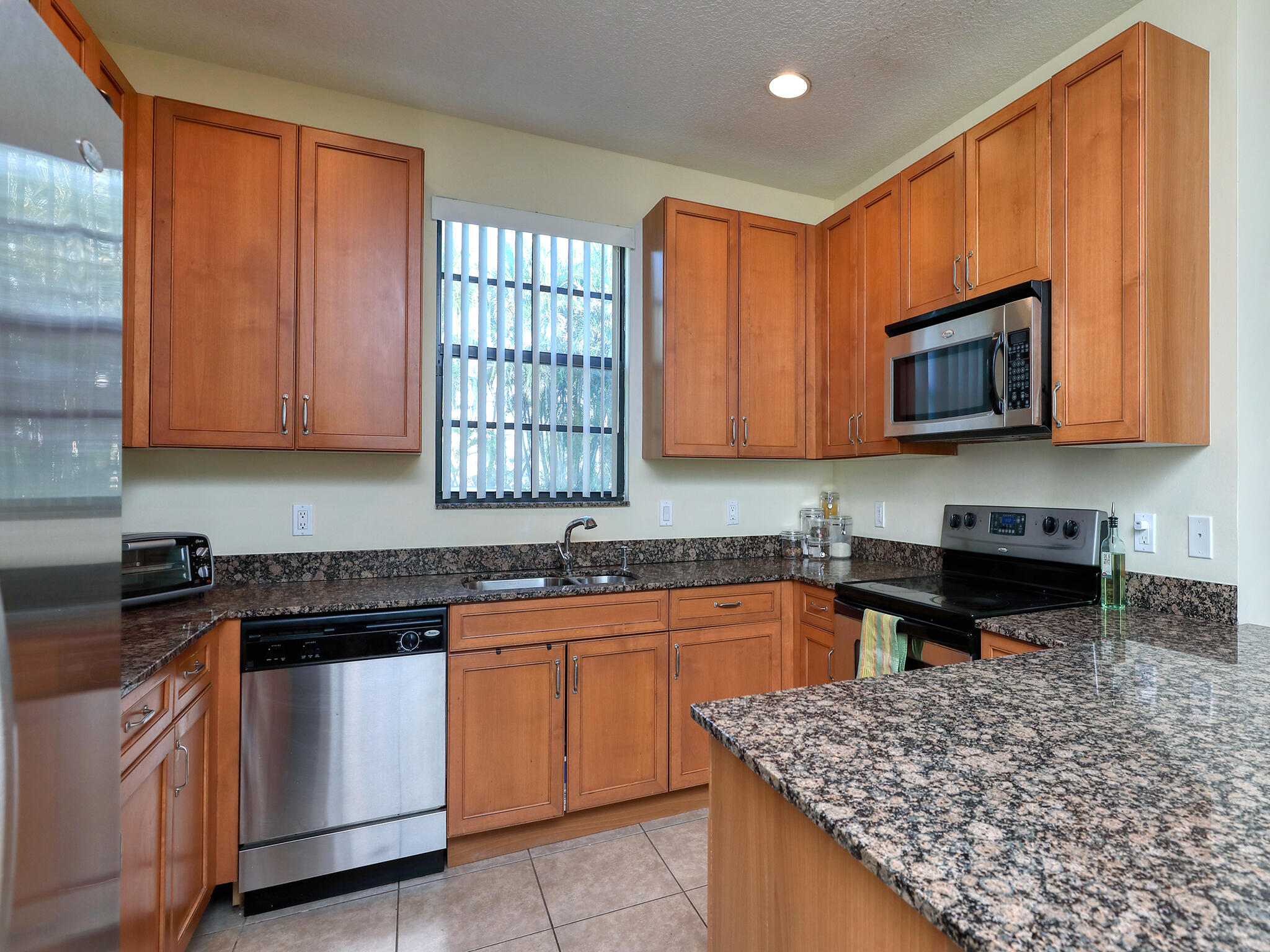 102 Astor Circle Delray Beach, FL 33484 - Photo 12 of 29 a kitchen with stainless steel appliances granite countertop a sink stove and microwave
