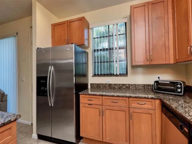 a kitchen with granite countertop stainless steel appliances a refrigerator a stove a sink and a window