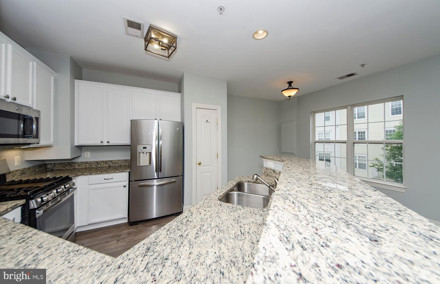 8069 Gatehouse Road, Unit 23 Falls Church, VA 22042 - Photo 16 of 43 a kitchen with granite countertop a refrigerator and a stove top oven