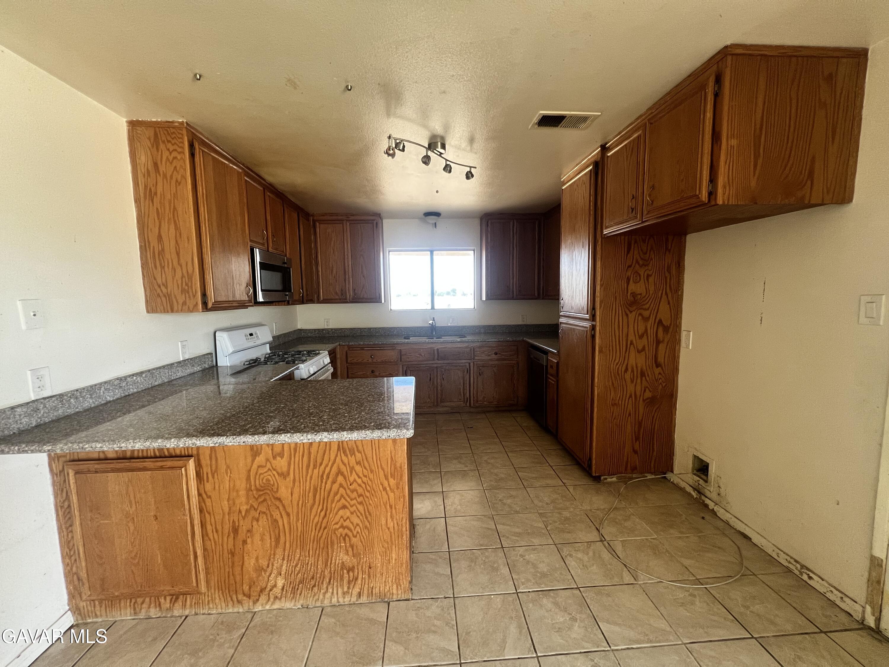 13632 Fran Street North Edwards, CA 93523 - Photo 9 of 18 a kitchen with stainless steel appliances granite countertop a sink refrigerator and cabinets