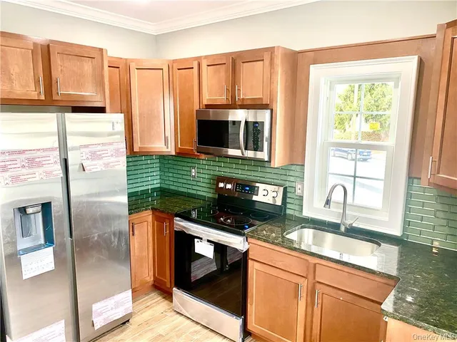 a kitchen with stainless steel appliances granite countertop a sink a stove and a microwave