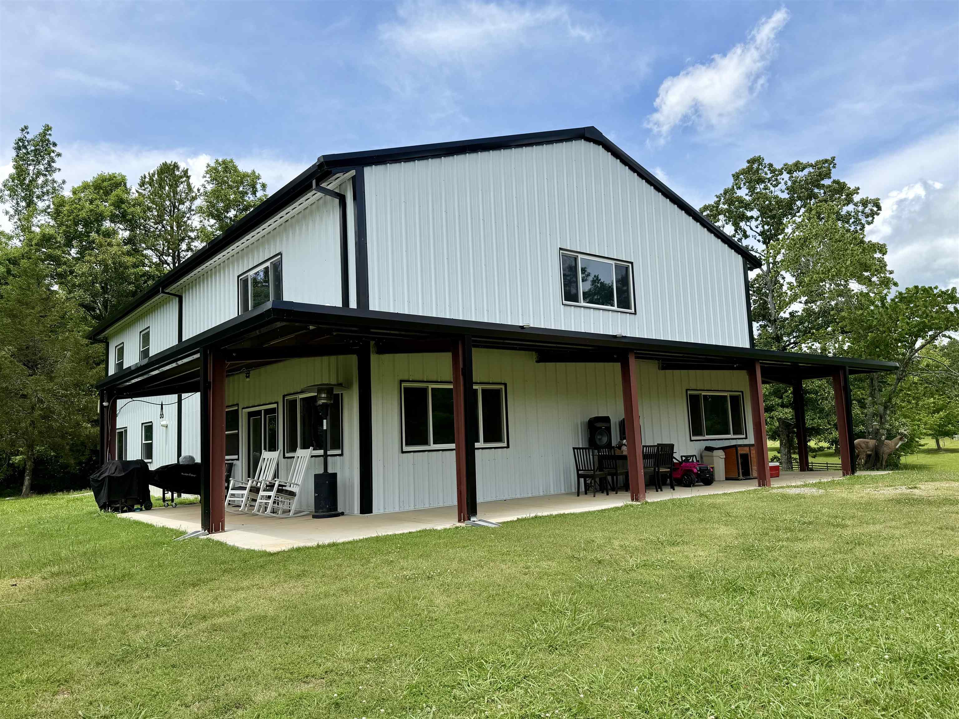 Modern barn-style residence featuring white metal siding and black trim