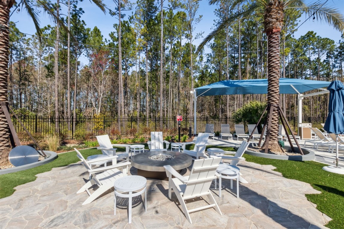 540 Jubilee Circle Yulee, FL 32097 - Photo 37 of 42 a view of a patio with couches table and chairs under an umbrella with a large tree