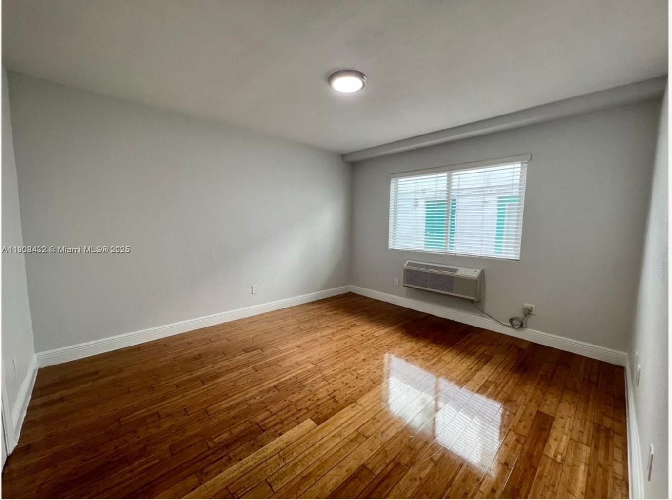 7315 Carlyle Avenue, Unit 10 Miami Beach, FL 33141 - Photo 7 of 9 an empty room with wooden floor and windows