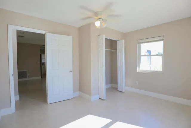 an empty room with closet and a ceiling fan