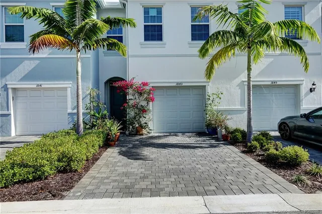 a front view of yellow house with a yard and potted plants