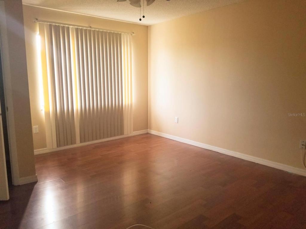 5859 Curry Ford Road, Unit 130 Orlando, FL 32822 - Photo 3 of 7 an empty room with wooden floor and windows with curtains