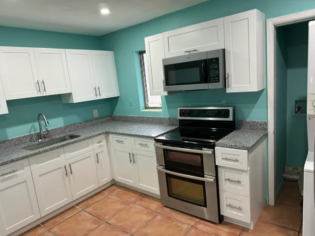 a kitchen with granite countertop white cabinets and stainless steel appliances