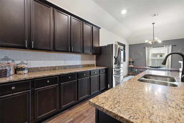 a kitchen with granite countertop a sink a counter space appliances and cabinets