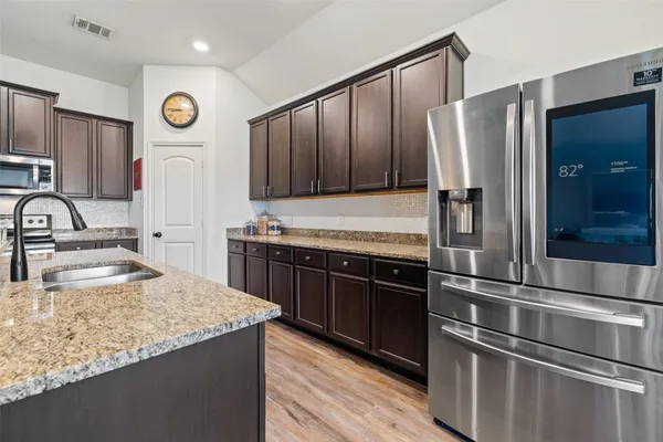 a kitchen with stainless steel appliances granite countertop a refrigerator and a sink
