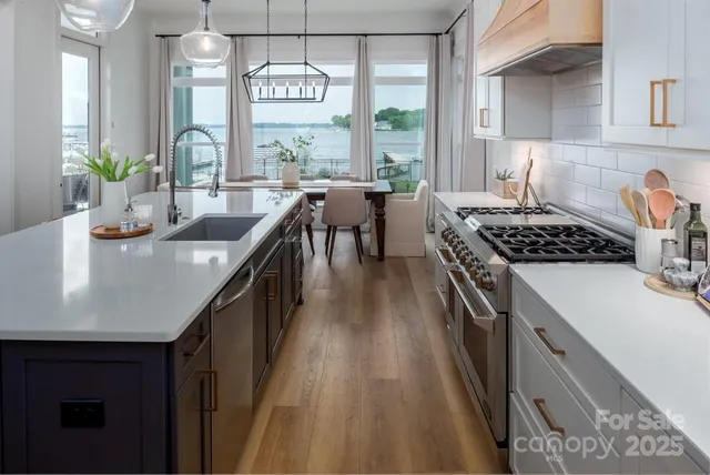 a kitchen with stainless steel appliances granite countertop a stove a sink dishwasher and cabinets with wooden floor