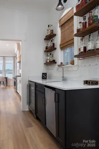 a kitchen with stainless steel appliances granite countertop a sink dishwasher and a black refrigerator with wooden floor