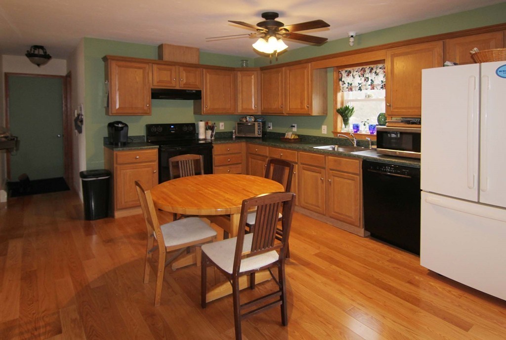 130 Plumtree Road Sunderland, MA 01375 - Photo 9 of 19 a kitchen with stainless steel appliances granite countertop a refrigerator a sink dishwasher a stove a dining table and chairs with wooden floor