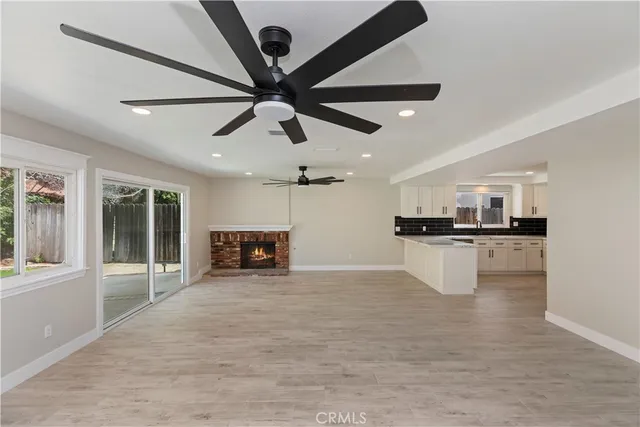a view of an empty room with kitchen and a window