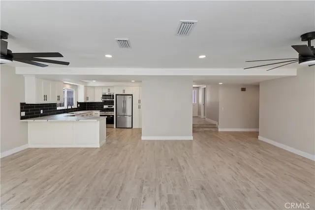a view of kitchen with stainless steel appliances a refrigerator and wooden floor