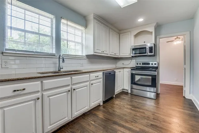 a kitchen with granite countertop white cabinets and stainless steel appliances