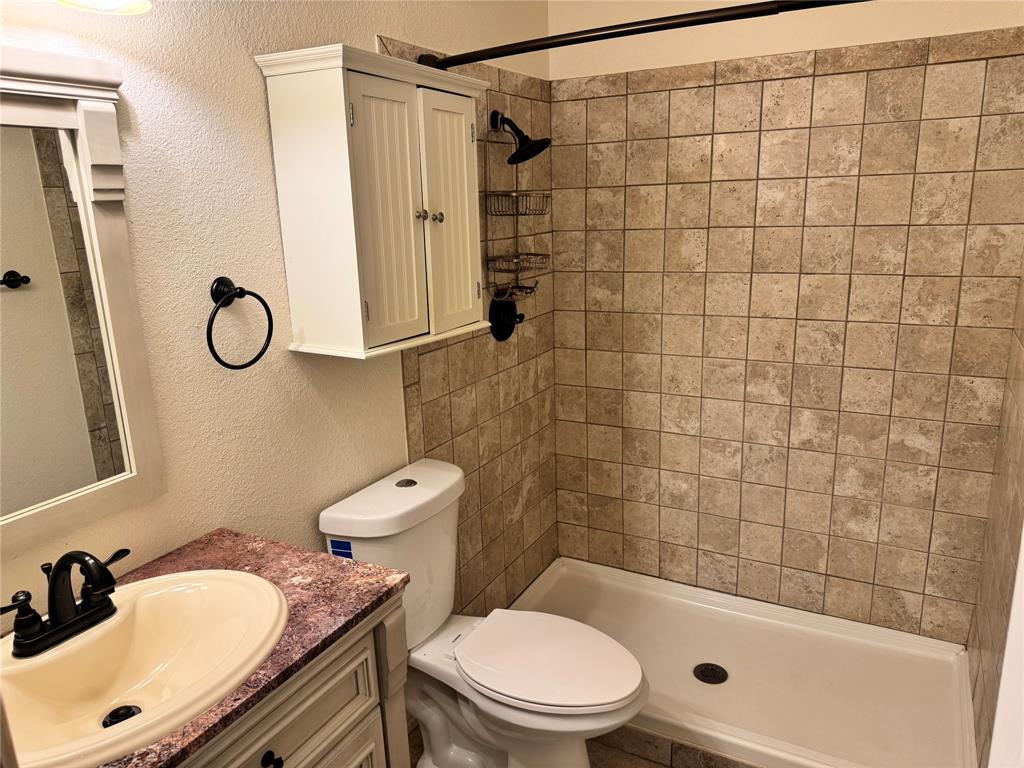 1824 North Binkley Street Sherman, TX 75092 - Photo 14 of 19 Bathroom featuring a textured wall, vanity, and a shower stall