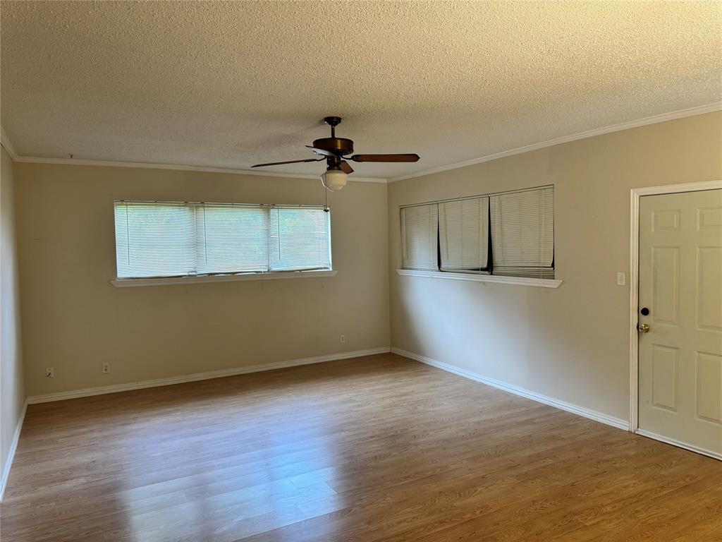 1824 North Binkley Street Sherman, TX 75092 - Photo 7 of 19 Empty room with ornamental molding, light wood finished floors, a textured ceiling, and ceiling fan