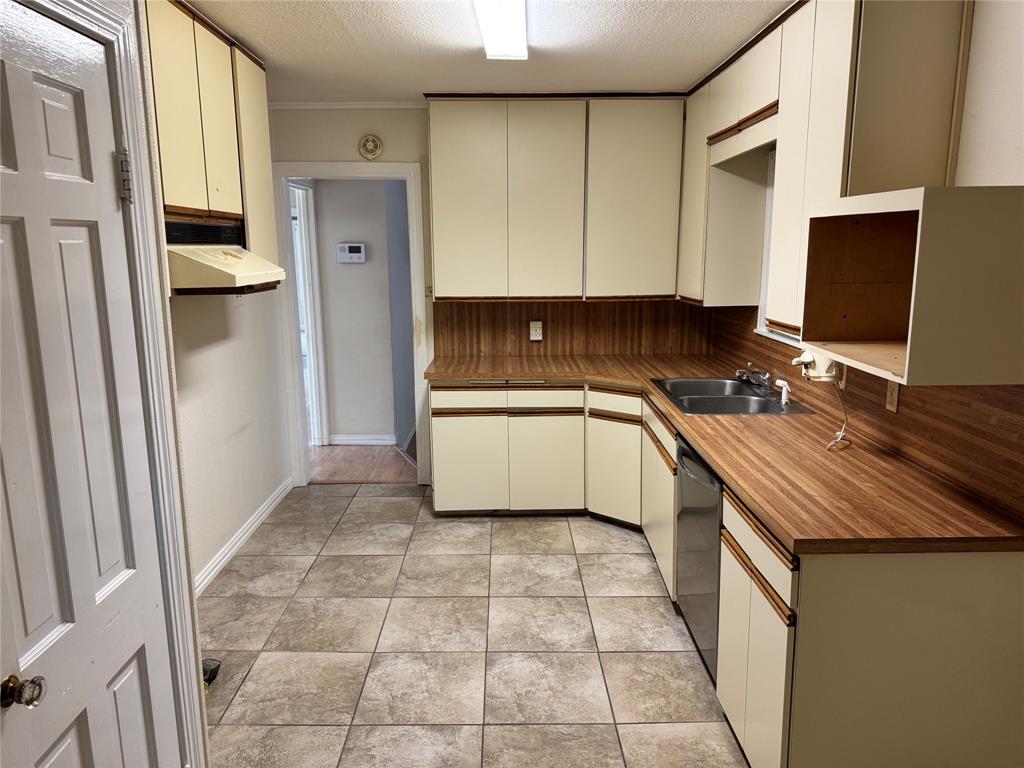 1824 North Binkley Street Sherman, TX 75092 - Photo 8 of 19 Kitchen featuring a textured ceiling, light tile patterned floors, stainless steel dishwasher, range hood, and cream cabinetry