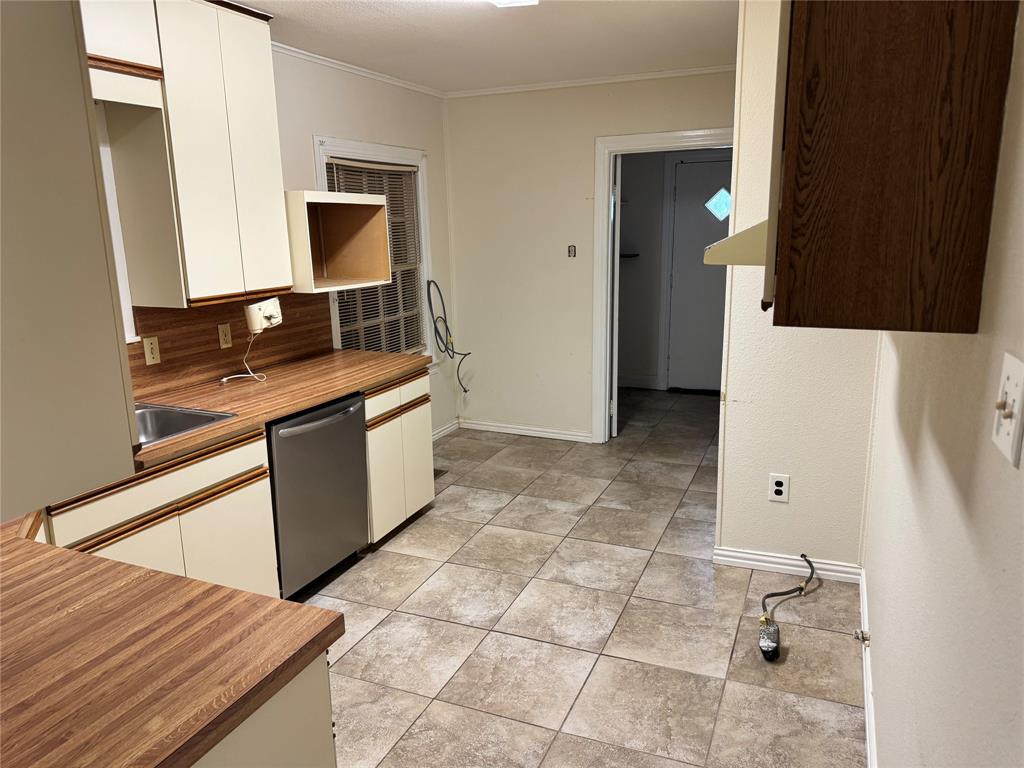 1824 North Binkley Street Sherman, TX 75092 - Photo 9 of 19 Kitchen featuring white cabinets, stainless steel dishwasher, crown molding, light countertops, and light tile patterned floors