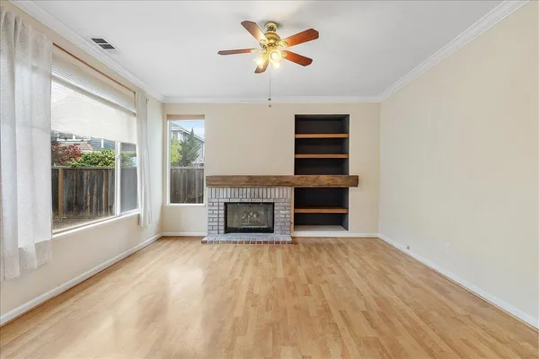a view of a livingroom with a fireplace a ceiling fan and wooden floor