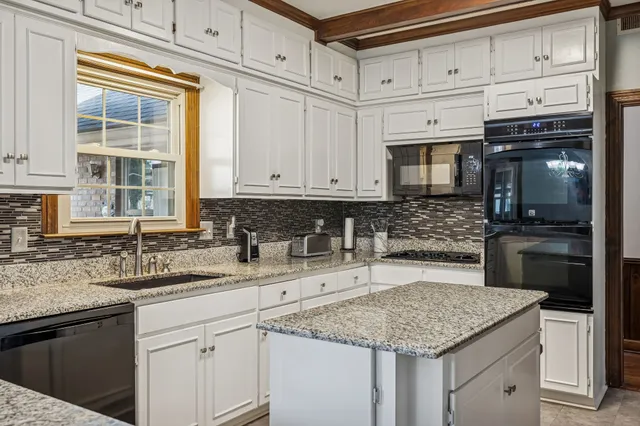 a kitchen with granite countertop a sink stainless steel appliances and cabinets
