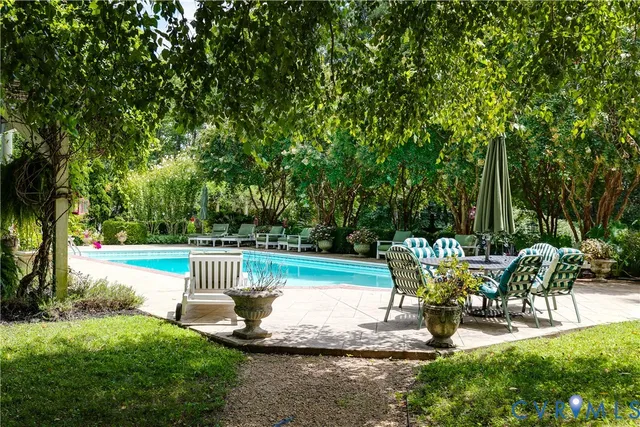 a view of a fountain in a yard with plants and large trees