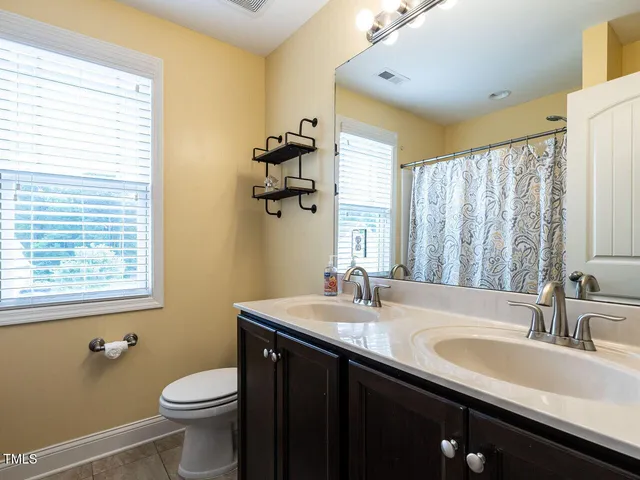a bathroom with a double vanity sink toilet and mirror