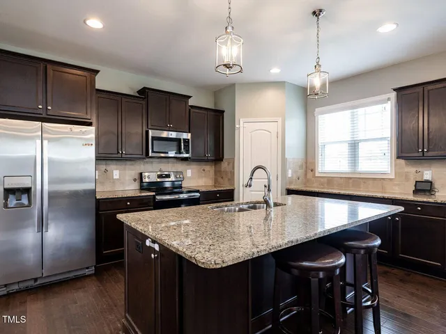 a kitchen with granite countertop stainless steel appliances a sink stove and refrigerator
