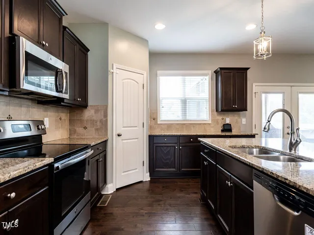 a kitchen with stainless steel appliances granite countertop a stove a sink and a microwave