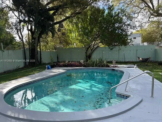 a view of a backyard with plants and large trees