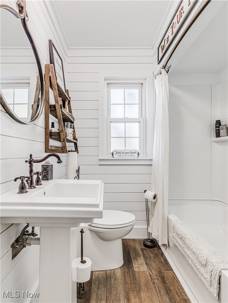 3553 Mogadore Road Mogadore, OH 44260 - Photo 21 of 29 Bathroom featuring wooden walls, toilet, wood-type flooring, shower / tub combo with curtain, and ornamental molding