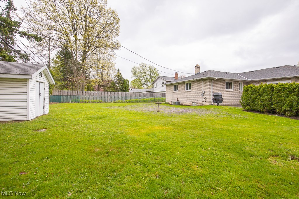4569 McFarland Road Cleveland, OH 44121 - Photo 29 of 29 View of yard with fence, an outdoor structure, central AC, and a shed