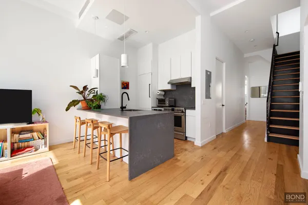 a kitchen with granite countertop a refrigerator a stove a sink a dining table and chairs with wooden floor