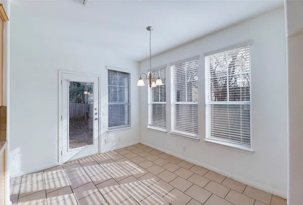 a view of an empty room with window and chandelier fan