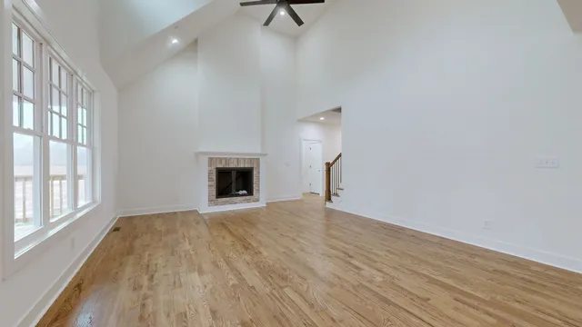 an empty room with wooden floor ceiling fan and windows