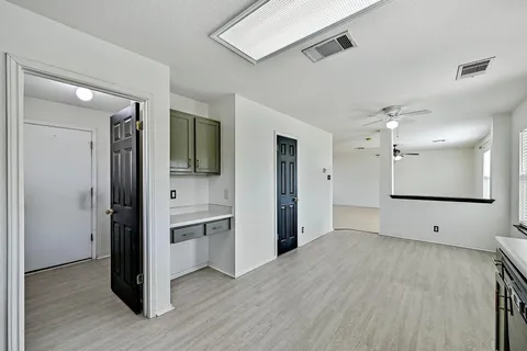 a view of an empty room with kitchen and a window