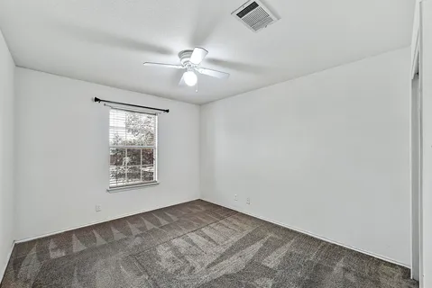 an empty room with windows and fan