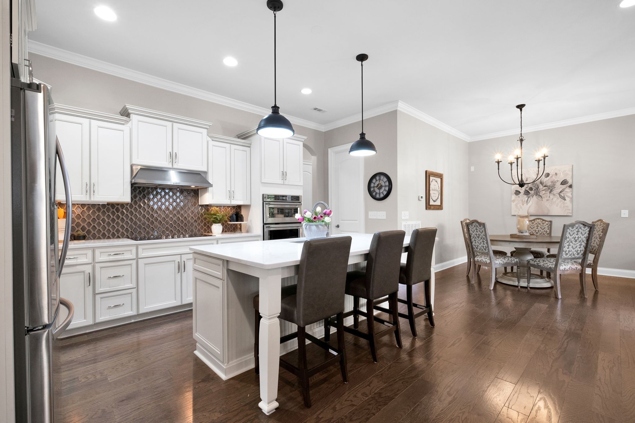 a kitchen with stainless steel appliances kitchen island granite countertop a table chairs and white cabinets
