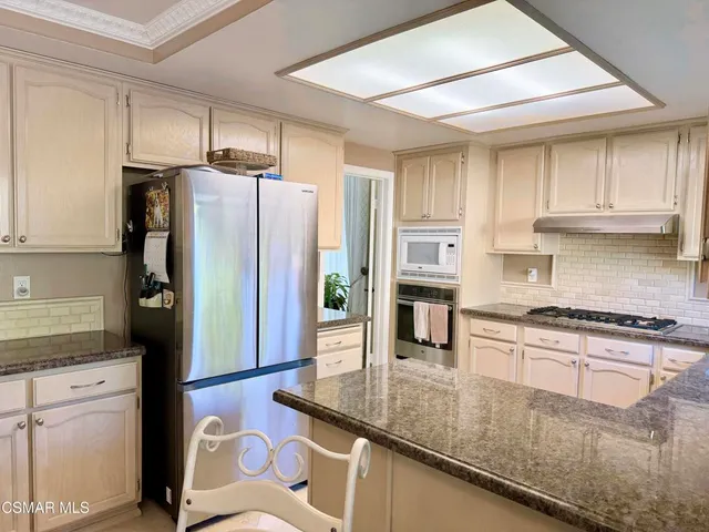 a kitchen with stainless steel appliances granite countertop a refrigerator a stove and a sink