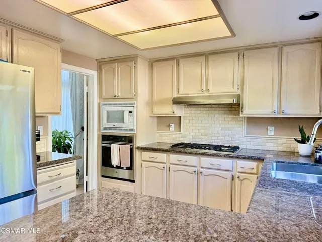 a kitchen with stainless steel appliances granite countertop a stove a sink and a refrigerator