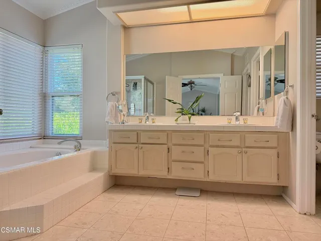 a spacious bathroom with a double vanity sink a mirror and a bathtub
