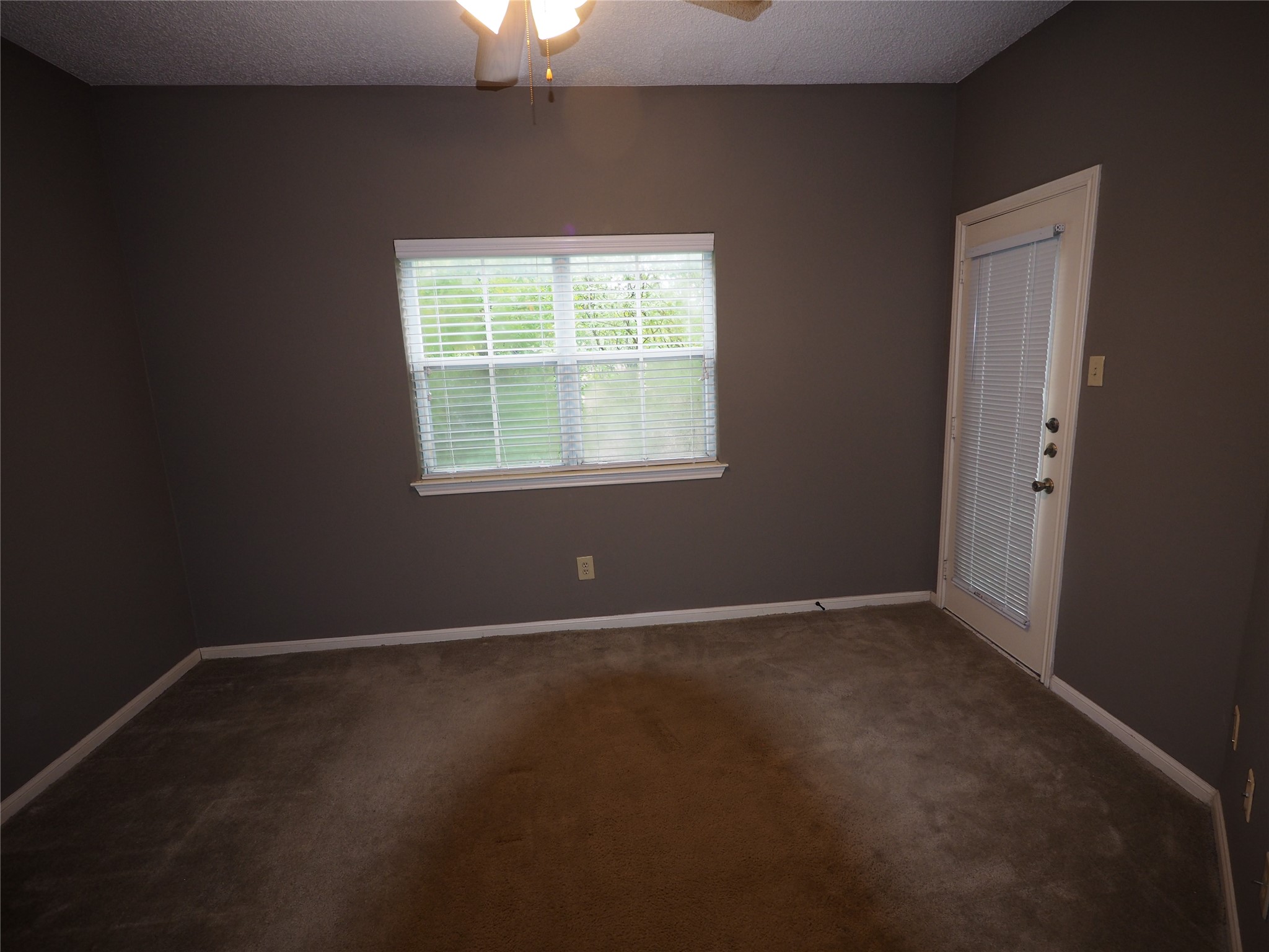 2508 Enfield Road, Unit 10 Austin, TX 78703 - Photo 11 of 17 Room featuring warm gray walls, light brown carpet, a ceiling fan with integrated lighting, a window with horizontal blinds, and an exterior access door