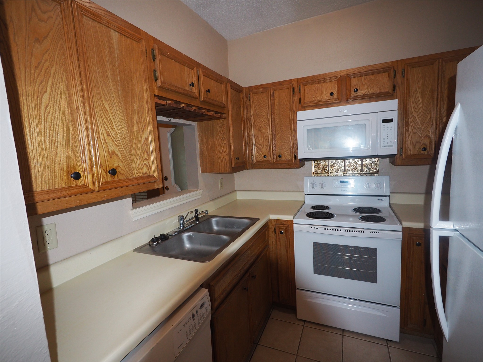 2508 Enfield Road, Unit 10 Austin, TX 78703 - Photo 7 of 17 Kitchen featuring wood-finish cabinetry, a double basin stainless steel sink, tile flooring, and white appliances including a range, microwave, and refrigerator