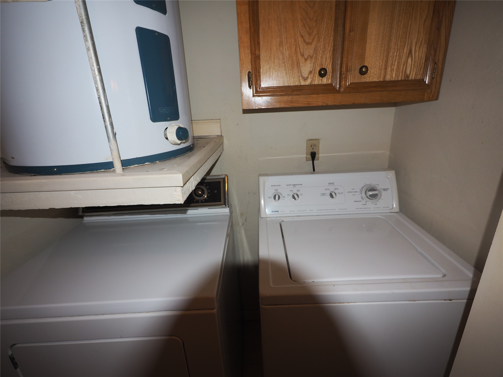 2508 Enfield Road, Unit 10 Austin, TX 78703 - Photo 8 of 17 Dedicated utility area featuring a water heater, upper cabinetry with wood-finish doors, a washing machine, and a dryer
